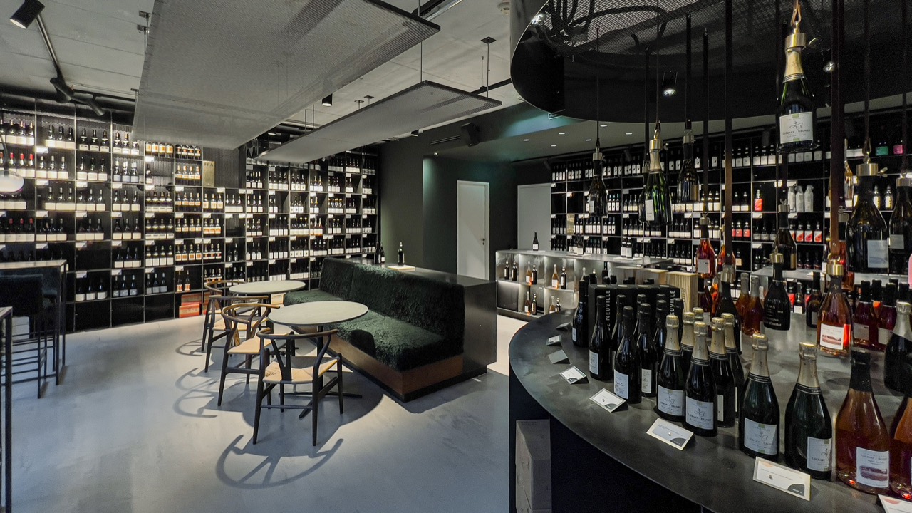 Projektfoto GREGORS boutique vinothek – geschwungene Verkaufstheke vor raumhohen Weinregalen